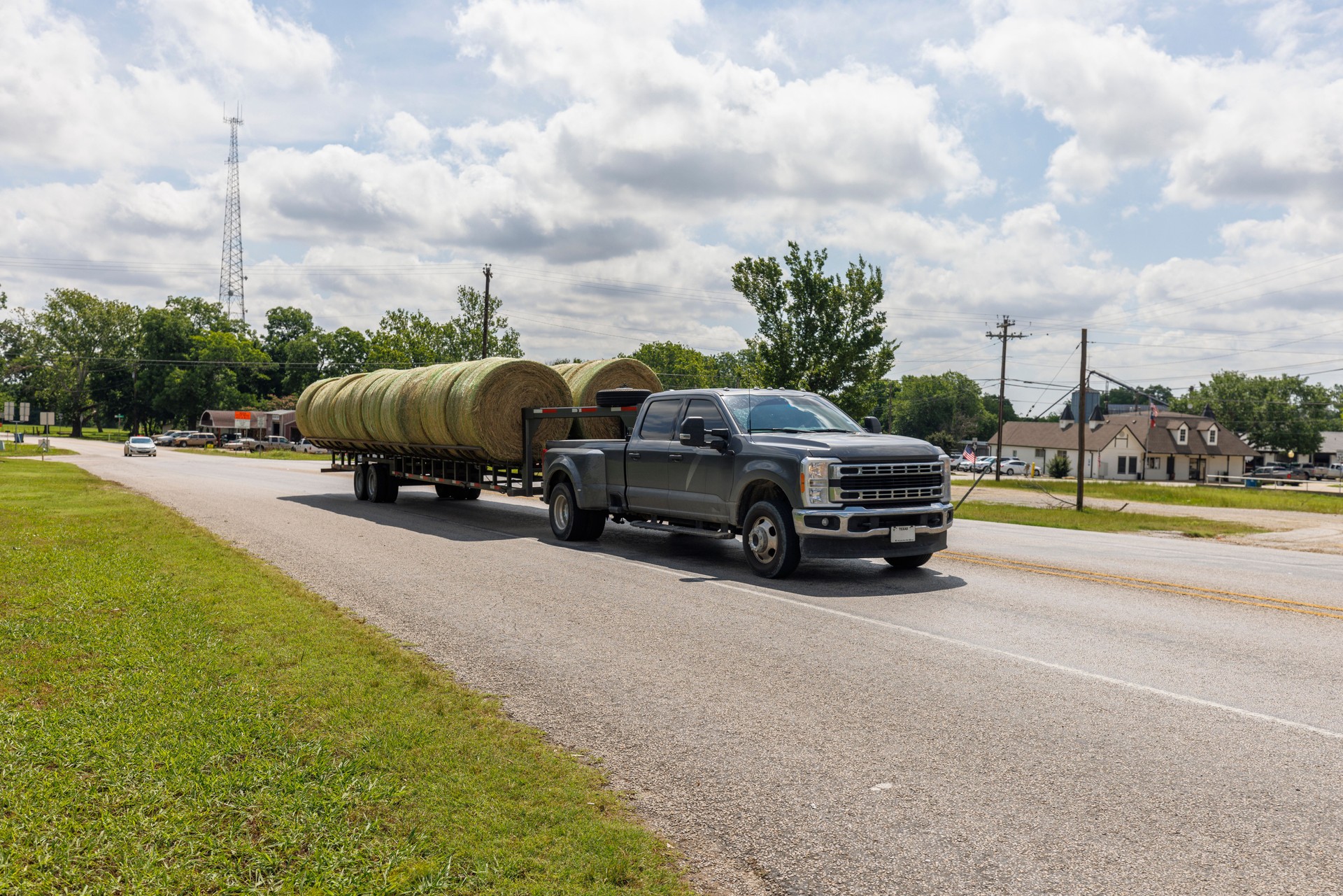 Transporting hay bales through rural America. Heavy-duty pickup tows trailer loaded with cylindrical bales in Aubrey, Texas.