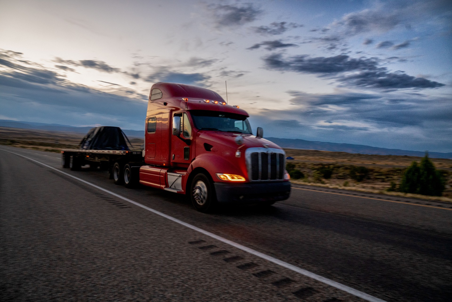 Flat Bed Long Haul Semi Truck Speeding Down a Four Lane Highway To Delivery Their Loads